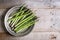 Banches of fresh green asparagus in a metallic jar on wooden background