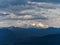 Band of Sunlight on Snow Between Dark Clouds and Mountain Slopes