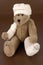 Bandaged teddy bear on brown background