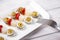 Banderillas of olives with spring onion and anchovies on a white plate next to a fork on wooden table.