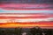 Bands of colourful clouds across the sky at sunset looking towards Portugal from Costa Esuri, Ayamonte, Spain