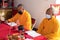 Bandung, Indonesia - January 8, 2022 : The monks sitting on the chair while praying on the altar in orange costumes