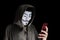 Bangkok, Thailand - May 6, 2018 : A hacker wears a mask wearing a robe. using smartphone theft and attacking data on cyberspace.