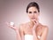 Banish bad skin days for good. Studio portrait of an attractive young woman applying moisturizer to her face against a