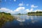 The bank of the Berezovka River is a tributary of the Volga. In summer, green trees and clouds are reflected in the