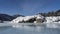 On the bank of the frozen river there are picturesque boulders covered with a layer of snow