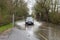 bank holidaycar passes through flooded road with warning and measuring gauge