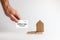 Bank investments and mortgages. Male hand holds Bank card near the trap with a cardboard schematic house. Copy space