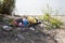 Bank of the river or lake. A pile of garbage on the beach - plastic bags, disposable cups, paper, glass