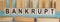BANKRUPT word written on wooden blocks on light blue background