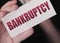 Bankruptcy on a card. Businessman holding a card with word Bankruptcy. Crisis business closing debts loss financial