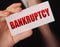 Bankruptcy on a card. Businessman holding a card with word Bankruptcy. Crisis business closing debts loss financial