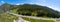 A banner aerial view of the direct road with cars in the Altai mountains surrounded by green forest and trees