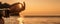 Banner. In blur closeup the hand of a young woman in bracelets. Practicing yoga on the beach with sunset. Keeps fingers