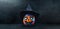 Banner with carved Jack-o-lantern. A decorated multicolored pumpkin in a black witch's hat on black background with copy