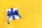 Banner of a Gift wrapped in white paper with a blue bow made of satin on festive yellow orange background