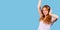 Banner, long format. Happy girl with curly red hair listens to music in big headphones and dances on a blue background.