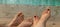 banner with male and female feet lie on the sand against the background of blue water. two pairs of legs. concept of