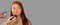 Banner. The red-haired girl at a beauty salon, is powdered on her face. The model looks away. Grey background