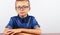 Banner Schoolboy in a blue shirt sitting at the table. Boy with glasses on white background Concept back to school