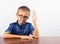 Banner Schoolboy in a blue shirt sitting at the table. Boy with glasses on white background Concept back to school