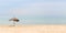 Banner of the seascape. Straw beach umbrella on a tropical sandy beach on a background of blue sea on a sunny day. Idyllic travel