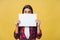 Banner sign woman peeking over edge of blank empty paper with copy space for text. Beautiful Caucasian woman looking