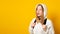 Banner. Surprised schoolgirl dressed white hoodie on yellow background with backpack looking away