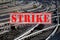 Banner with text STRIKE over lots of railroad tracks and switches, trade union concept for fair pay and working conditions in the