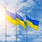 Banner with three Ukrainian flags on a background of blue sky and rising sun
