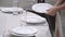 Banquet manager puts textile napkin under white plate. Woman serves table.