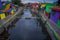 BANYUWANGI, INDONESIA: Water channel seen from bridge with colorful houses on both sides, charming neighborhood, cloudy