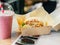 Bao with tofu in carton and Pink fruit cocktail smoothie in plastic cup with white-red spiral tube for milkshakes stand on table