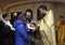 Baptizing for baby. Man and woman standing with a baby on hands and priest cutting off a patch of hairs from head of child