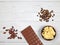 Bar of milk chocolate, carob, cocoa butter and cocoa beans on light wooden background