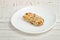 Bar of muesli on a white saucer. White wooden table