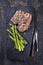 Barbecue dry aged wagyu porterhouse beef steaks with green asparagus on a rustic charred wooden board