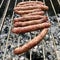 Barbecue with fiery Bavarian sausages on grill in garden outdoors