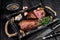 Barbecue Grilled rump cap or brazilian picanha beef meat steak in a wooden tray. Black wooden background. Top view