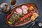 Barbecue Lamb Roast with skewered tomatoes and olives on a rustic plate