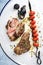 Barbecue leg of lamb with tomato skewer on a white rustic tray