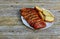 Barbecue pork steak slices on white plate. Grilled potatoes on wood table.