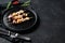 Barbecue with seafood. Kebab on wooden skewers with shrimp, octopus, squid and mussels. Black background. Top view. Space for text