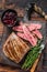 Barbecue sliced flank beef meat steak on a wooden cutting board. Dark wooden background. Top view