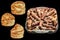 Barbecued Minced Meat Loaves with Chicken Ties in Glass Baking Pan and Puff Pastry Sesame Cheese Buns Isolated on Black Background