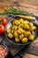 Barbecued organic olives with herbs in plate. Wooden background. Top view