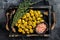Barbecued organic olives with herbs in plate. Wooden background. Top view. Copy space