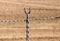 Barbed wire fence with a background of a dry, tilled field.