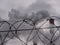 Barbed wire with industrial smoking pipes background