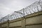 Barbed wire spirals on a concrete fence. The metaphor of imprisonment and lack of freedom.